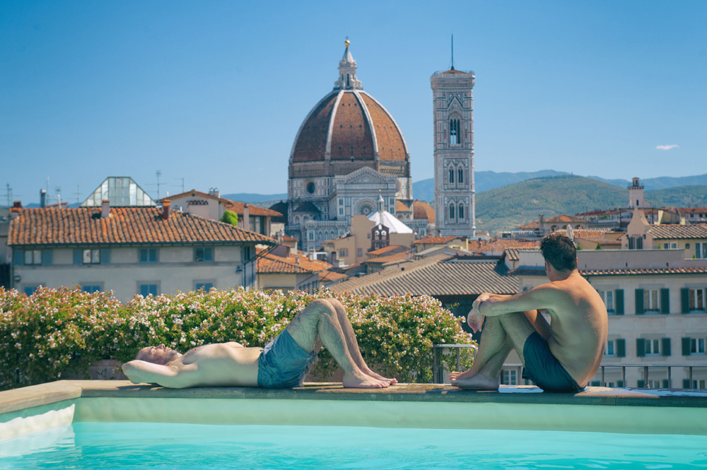 2 men relaxing poolside with the Duomo in Florence in the background, Italy.