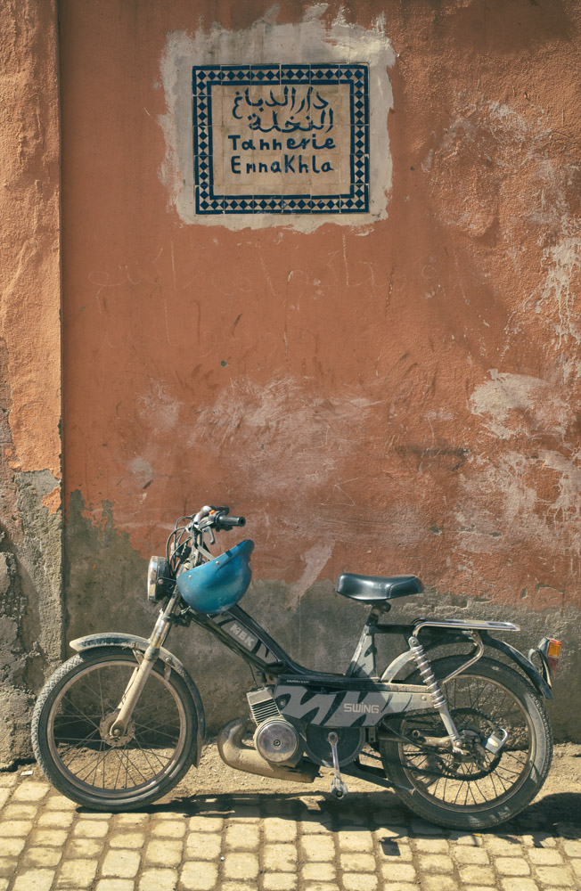 A motorbike standing next to a pink wall in the Marrakech Medina, Morocco.